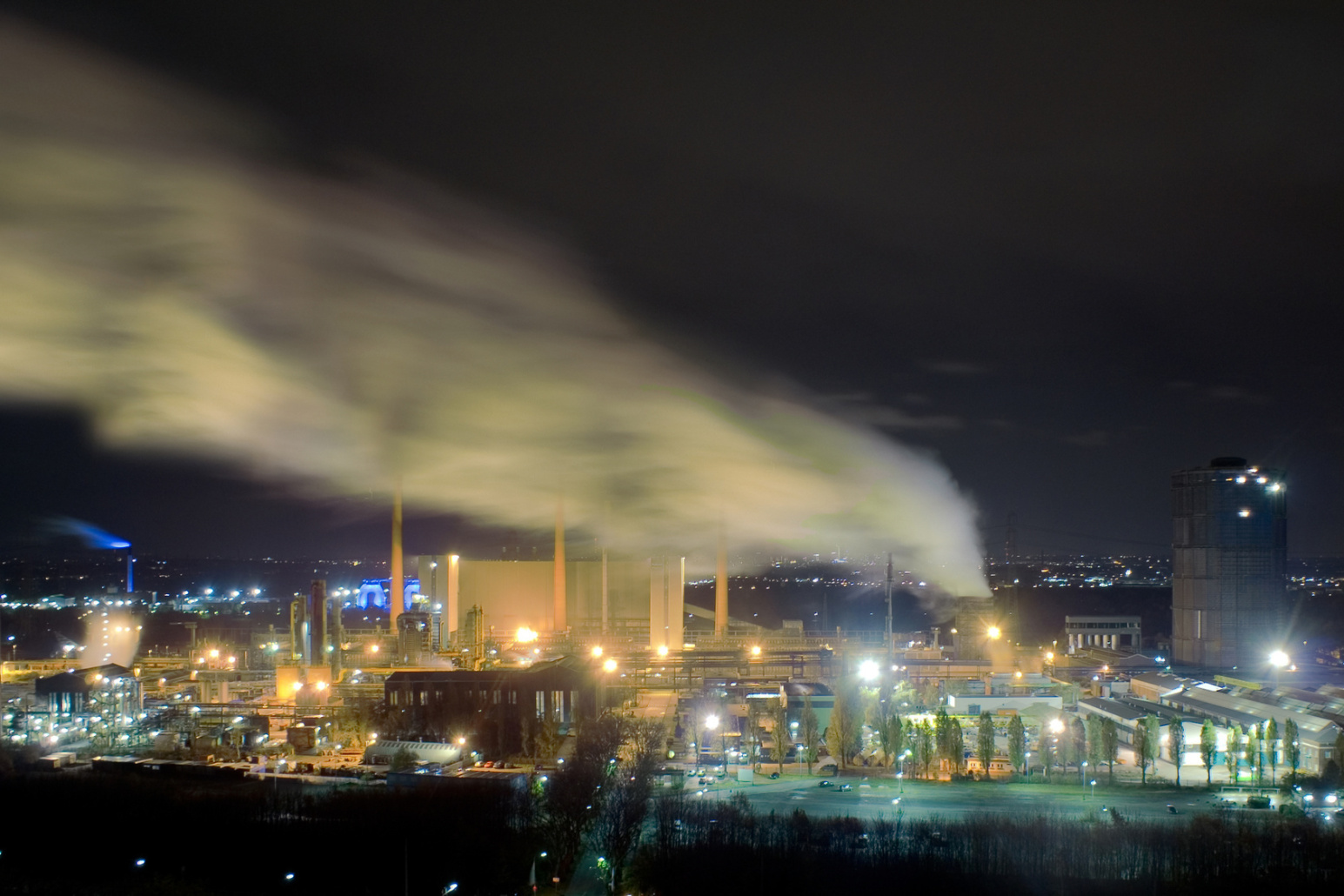 Industrieanlage bei Nacht mit aufsteigendem Rauch in Essen, Kurtz Detektei Essen